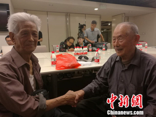 闫玉成老人(右)与另一位受害中国劳工赵宗仁握手。 张尼 摄