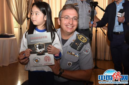 巴西圣保罗州军警总司令甘巴罗尼为华裔儿童赠送手册。（莫成雄　摄）
