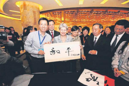 联合国教科文总干事博科娃(左二)体验陈翔(左一)四力法写出和平二字。旁为中国教育部部长袁贵仁(右二)。(新加坡《联合早报》)