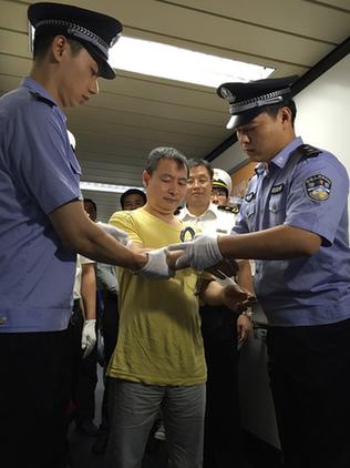 嫌疑人黄某被戴上手铐。蔡岩红摄 嫌疑人黄某被戴上手铐。蔡岩红摄