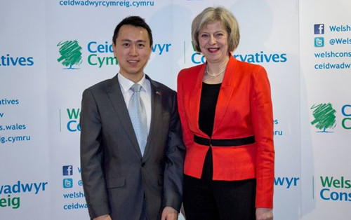 2015年初，何易与特丽莎‧梅在保守党党会上合影。 