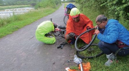 三位长者在路边维修爆胎的自行车。(《欧洲时报》/受访者供图)