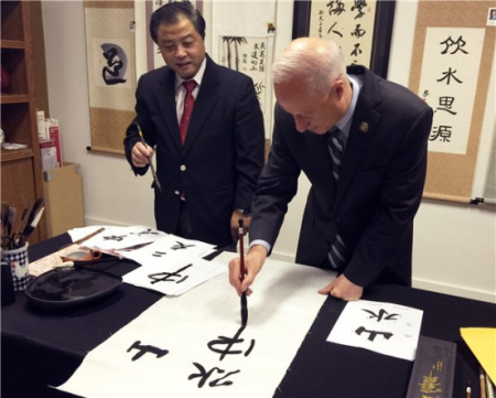 马克·考夫曼手握毛笔书写汉字（美国《中美邮报》）