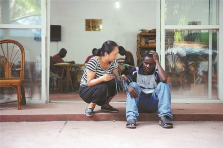 学员厄内斯特·夸（右）在编织过程中几次失败，心情沮丧，指导教师胡霞安慰并鼓励他继续努力。