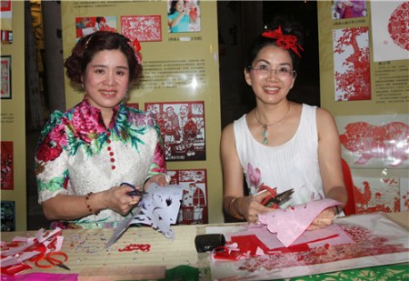 中国工艺美术大师高少苹（右）及张峥嵘在现场展现民间剪纸艺术技巧。