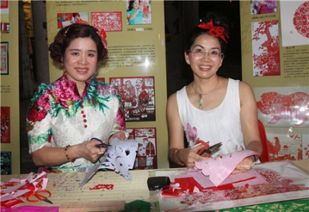 中国工艺美术大师高少苹(右)及张峥嵘在现场展现民间剪纸艺术技巧。 中国工艺美术大师高少苹(右)及张峥嵘在现场展现民间剪纸艺术技巧。