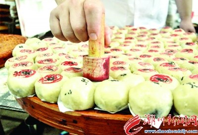 在生饼皮上面缀上黑芝麻,底部垫上白纸片后平整摆放。按传统惯例,在生饼皮上盖上铺号印章。 在生饼皮上面缀上黑芝麻,底部垫上白纸片后平整摆放。按传统惯例,在生饼皮上盖上铺号印章。