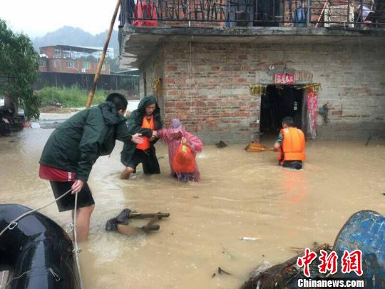 在齐大腿深的水中，消防官兵扶着受灾民众趟过深水区。消防供图