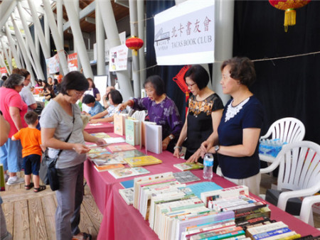 北卡书友会为游客写书法和义卖中英文书籍。（美国《世界日报》/王明心 摄）