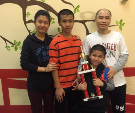 陈榕越(右二)获冠军捧杯，爸爸妈妈和哥哥都为他骄傲。(美国《世界日报》/刘大琪 摄)