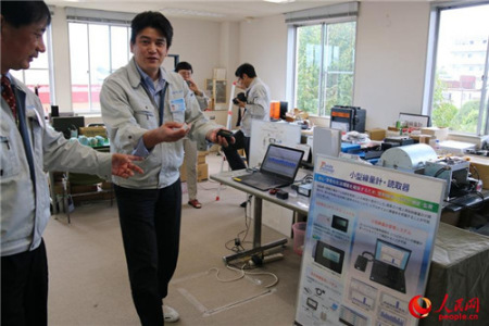 王社长让工作人员展示小型辐射监测仪与读取器。