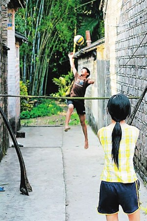一根细竹竿两头架着椰子树枝干，村中小巷便成了文昌当地孩童的排球场。 图片来自本报资料库