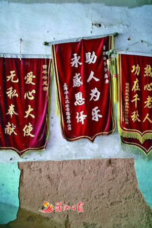 图为老人家墙上挂满受助学生送来的锦旗。 图为老人家墙上挂满受助学生送来的锦旗。