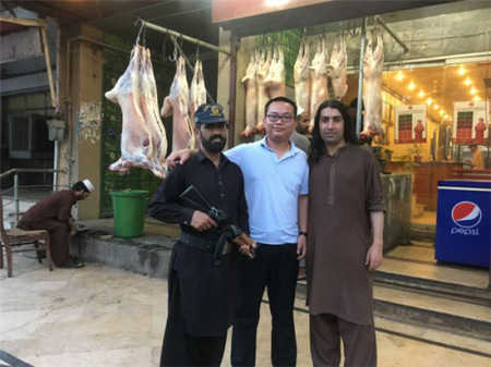 王建龙(中)与伊斯兰堡一家餐馆老板和保安合影。餐馆是公共场所，也有持枪保安