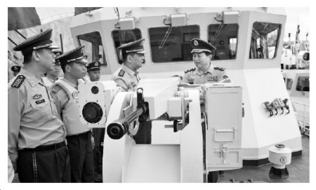 图为公安部边防管理局副局长高连斌少将检查水上支队执法船艇武器装备。 