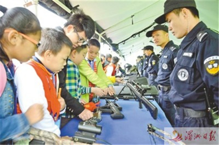 日前，市公安局举行警营开放日，邀请各界群众代表走进警营，体验警营生活、了解公安工作，进一步促进警民关系。图为部分学生代表正在了解枪械知识。 记者 吴伟锋 摄