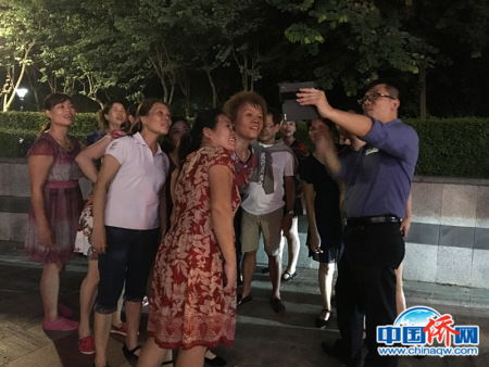 作者向东盟记者和跳广场舞的大妈们展示手机拍摄的视频。