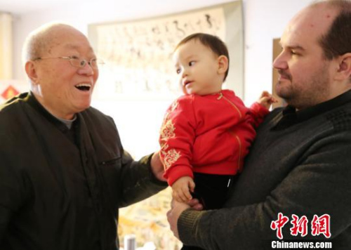 弗莱恩抱着儿子鲁克斯给长辈拜年。 胡洪涛 摄 弗莱恩抱着儿子鲁克斯给长辈拜年。 胡洪涛 摄