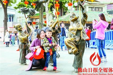 禅城祖庙景区，一对母子正在景区门前的雕塑前拍照。/佛山日报记者王澍摄