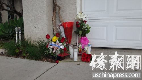门口摆放着长明灯和鲜花，表达了人们对受害者黄闵的追思和悼念。(美国《侨报》/高睿 摄)