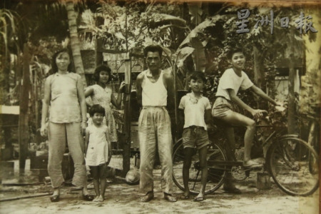 从海南岛飘洋过海而来的花生饼第一代创始人王芳泽（中），当年就是骑着这架旧式的脚踏车，在峇市各地兜售花生饼。（马来西亚《星洲日报》）
