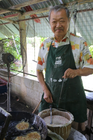 陈琼文（左）和陈川荣父子俩秉持着祖辈的手艺，以手工制作花生饼此传统小食。（马来西亚《星洲日报》）