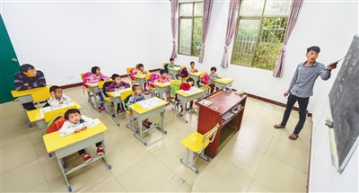 代课老师吴志平在给学生上课，父亲吴光明坐在后排认真地观察。