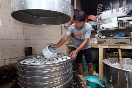 何修万将米浆一一倒入铝制小碗，并送入蒸炉内蒸熟。