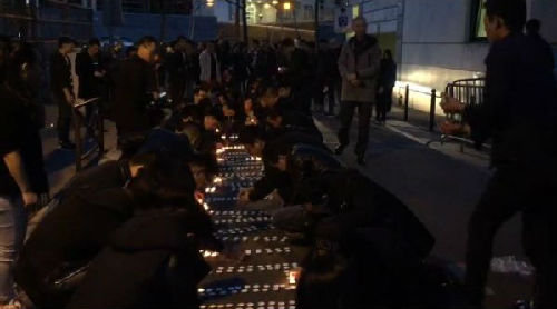 当地华人摆放蜡烛为死去同胞祈福。(27日晚视频截图/韩冰 摄)