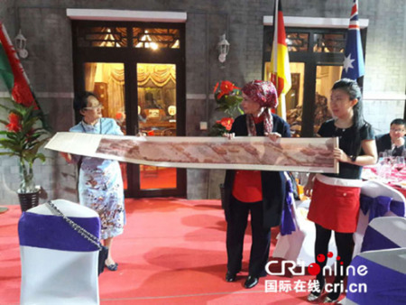 任洁老师(左一)将中国著名画家刘洪宽大师的工笔画《丹衢宫阙》丝绸长卷送文化使者娜迪雅公主。