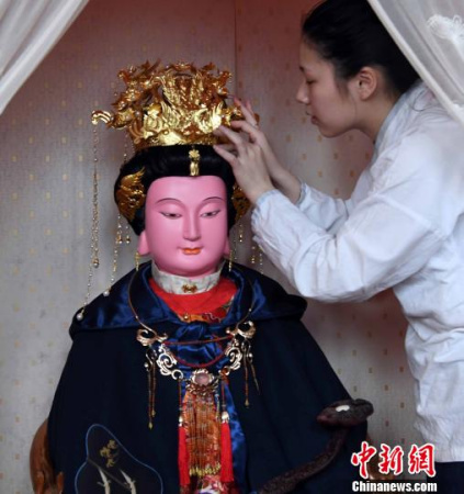一名福州三坊七巷郎官巷天后宫道士更衣沐手、上香拜谒后为妈祖软身神像戴上凤冠。 记者刘可耕 摄 一名福州三坊七巷郎官巷天后宫道士更衣沐手、上香拜谒后为妈祖软身神像戴上凤冠。 记者刘可耕 摄