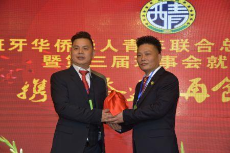 叶建伍(左一)从创会会长陈晓敏手中接过了代表协会荣誉与未来的大印和会旗。(西班牙《欧华报》 供图) 叶建伍(左一)从创会会长陈晓敏手中接过了代表协会荣誉与未来的大印和会旗。(西班牙《欧华报》 供图)