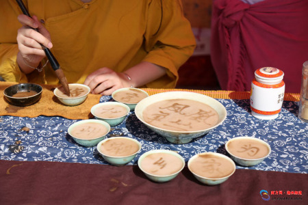 活动现场，茶艺人表演茶百戏，在茶沫上用毛笔写字。