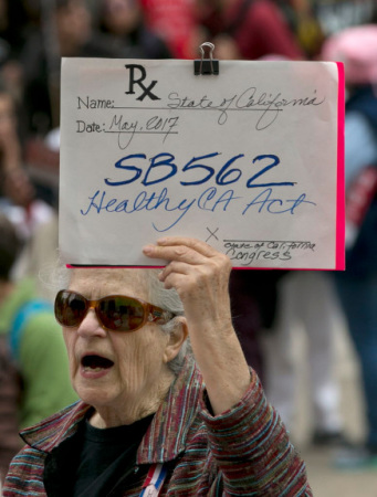 参加游行的老人手举白板倡议SB562。(美国《侨报》/美联社图片)
