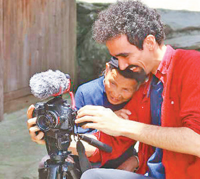 巴西青年帕维尔在广西龙脊小寨，给瑶族老人展示拍摄好的画面。 　　谢汶宏摄