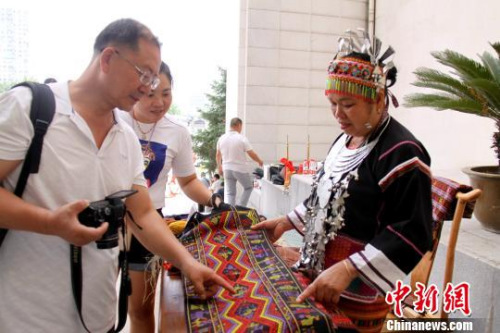 云南省广南县文化馆工作人员陈应文与和海南黎族纺织技艺传人符西利交谈。　曾洁 摄