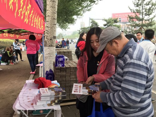 图为省侨联志愿者向考生家长赠阅刚刚印制的《吉林侨联》杂志。
