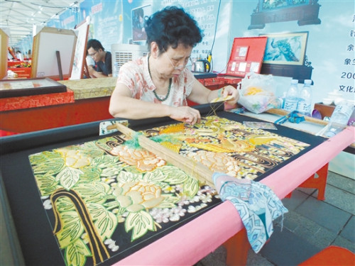 潮绣传承人李淑英在展示刺绣技艺，她手上的这幅刺绣已经绣了将近一年。