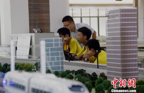  在教师指导下，华裔青少年操作高铁运行沙盘系统，模拟车站值班员接发列车。 朱柳融 摄