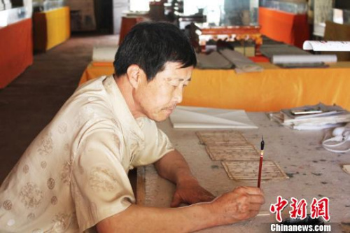 在甘肃敦煌市的一处民俗旅游地——月牙泉小镇内,傅有宏伏案临摹敦煌汉简。 徐雪 摄 在甘肃敦煌市的一处民俗旅游地——月牙泉小镇内,傅有宏伏案临摹敦煌汉简。 徐雪 摄