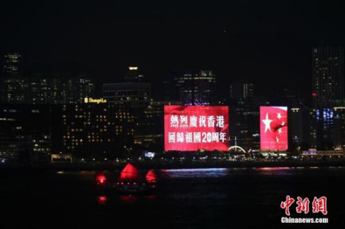 香港回归祖国二十周年庆典临近，香港庆回归气氛渐浓，6月27日晚，在维多利亚港湾两侧霓虹闪烁，大厦上的电子屏“升起”巨幅五星红旗和紫荆花区旗，交替展现，并有“热烈庆祝香港回归祖国20周年”、“祝贺香港回归20周年”字样。 <a target='_blank' href='http://www.chinanews.com/'>中新社</a>记者 盛佳鹏 摄