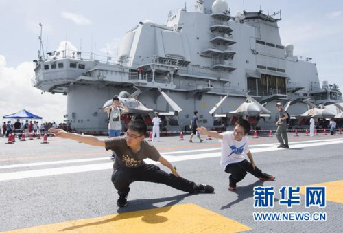 7月9日，两名青少年在辽宁舰的飞行甲板上模仿“航母STYLE”动作。新华社记者 刘昀 摄