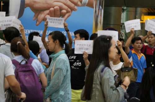 进行纠察的导游们高举手卡，抗议本地旅行团雇用无牌中国导游。（马来西亚《星洲日报》）