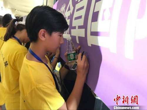 华裔师生在“不忘历史珍爱和平——南京紫金草国际和平学院海外华裔青少年寄语留言”横幅上签名。江苏省侨办