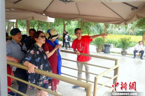 图为志愿者为等候参观的游客介绍莫高窟景区相关内容。　李文城 摄