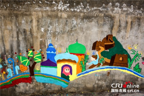 孩子们同志愿者一起在墙上涂鸦，上面有长城、竹子、练武功的女孩等中国元素