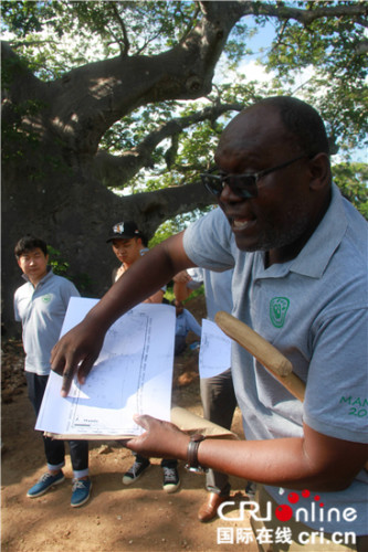 查普·库辛巴教授在发掘现场展示曼达古镇范围图。 （王新俊 摄）