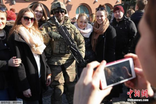 资料图：当地时间2015年3月24日，波兰比亚韦斯托克，美国士兵与当地居民在当地市集广场合影。美国士兵从爱沙尼亚返回其在德国巴伐利亚州的基地。
