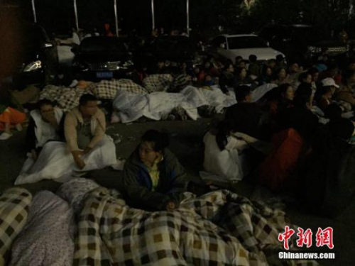 图为九寨沟景区内,许多游客不敢继续待在酒店内,裹着厚衣服和毛毯来到街上席地而睡。 徐广 摄 图为九寨沟景区内,许多游客不敢继续待在酒店内,裹着厚衣服和毛毯来到街上席地而睡。 徐广 摄