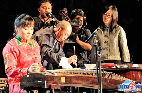 在中印尼宗教交流文艺演出中，作者（左二）和着古筝在写中国书法。(图片均由作者提供)